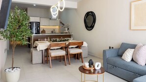 Una sala moderna con comedor, un sofá gris, una mesita de centro y una planta en maceta.
