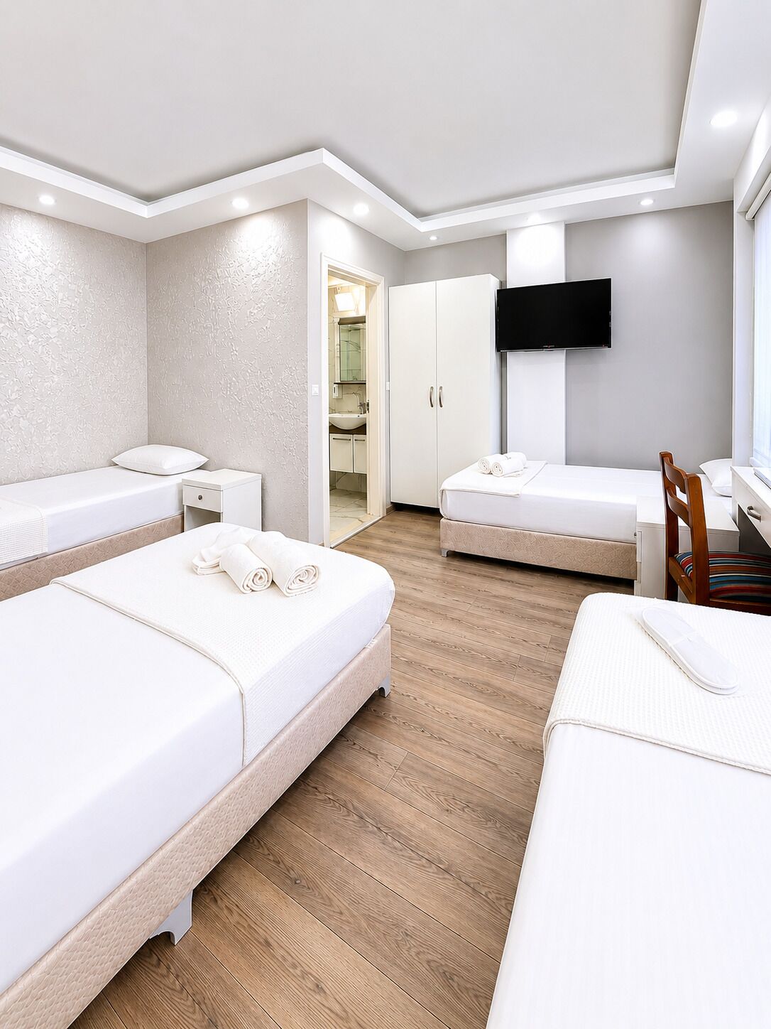 Hotelkamer met twee bedden, een televisie, een kledingkast en een badkamer zichtbaar door een geopende deur.