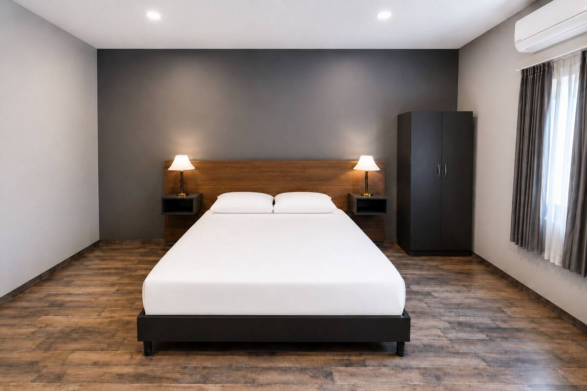 A modern hotel room with a large bed, two bedside tables with lamps, a wardrobe, and a large window with curtains.