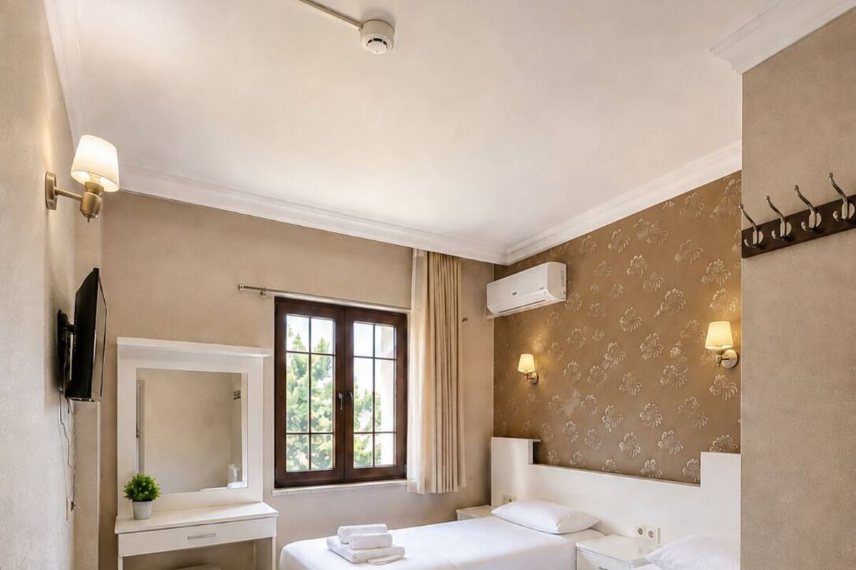 A hotel room with two beds, a desk, a TV, and a window with curtains.