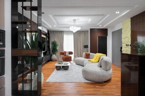 A modern living room with a grey sectional sofa, a coffee table, and a large plant. - ARI RESIDENCE (Lagos)