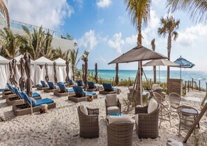 Eine Strandlounge mit Liegestühlen und Korbmöbeln mit Blick auf den Ozean.