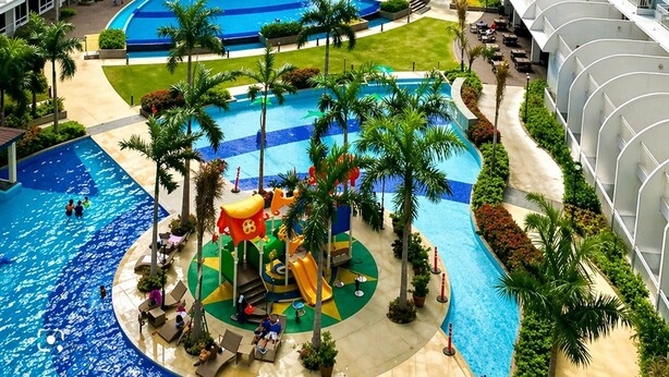 A large hotel with multiple high-rise buildings, a central swimming pool, and surrounding greenery. - Luxe 1-bedroom Condo Front of Mall of Asia With City View in Pasay (Pasay)