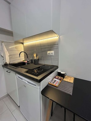 A compact kitchen with a built-in dishwasher, a gas stove, and a small countertop. - Budget Cute Studio in Thessaloniki Center (Thessaloniki)