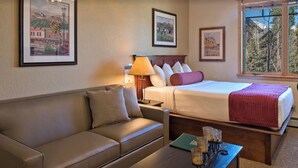 Ein Hotelzimmer mit einem Bett, einem Schlafsofa, einem Nachttisch, einer Lampe, einem Couchtisch und gerahmten Bildern an der Wand.