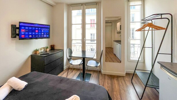 Une chambre d’hôtel compacte comprenant un lit, un bureau, une télévision et un balcon avec vue.
