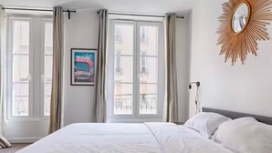 A hotel room with a large bed, a sunburst mirror, and a balcony view. - UrbanFlat 203 + 202 - 249 Saint Denis SD1 (Paris)