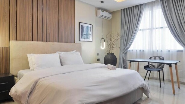 Una habitación de hotel moderna con una cama grande, una mesita pequeña y una silla.
