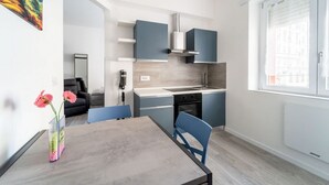 A modern kitchen with blue cabinets, a built-in stove, and a window with blinds.