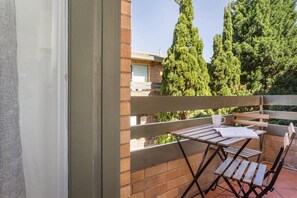 A balcony with a table and chairs, a window, and a view of trees and a building. - Refined comfort 1 bed Neutral Bay w parking & balcony (Neutral Bay)