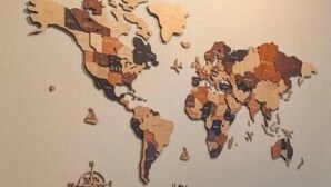 Un mural con un mapa del mundo, una planta en maceta y una pequeña brújula.