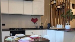 Una cocina moderna con armarios blancos, una mesa de comedor de madera y una silla blanca.