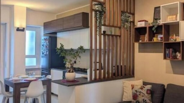 Un espacio moderno para vivir con comedor, sofá y área de cocina separada por un panel de madera.