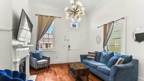 A living room with a fireplace, a sofa, a coffee table, and a blue armchair. - 3BR Gem Near Garden District (New Orleans)