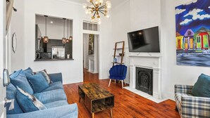 A living room with a fireplace, a television, and a painting on the wall. - 3BR Gem Near Garden District (New Orleans)