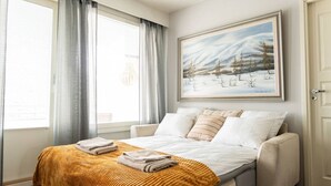 Ein Schlafzimmer mit Bett, einem Fenster mit Vorhängen, einem Bild an der Wand und einer Tür.