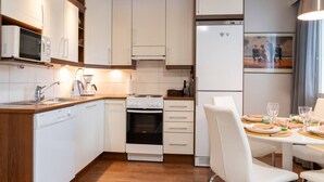 Eine moderne Küche mit weißen Schränken, einem Einbauofen, einer Mikrowelle und einem Kühlschrank.