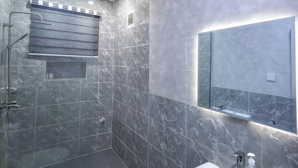 A modern bathroom with a shower, toilet, and sink, featuring marble tiles and a glass shower enclosure. - VENUS HOTEL (Onitsha)