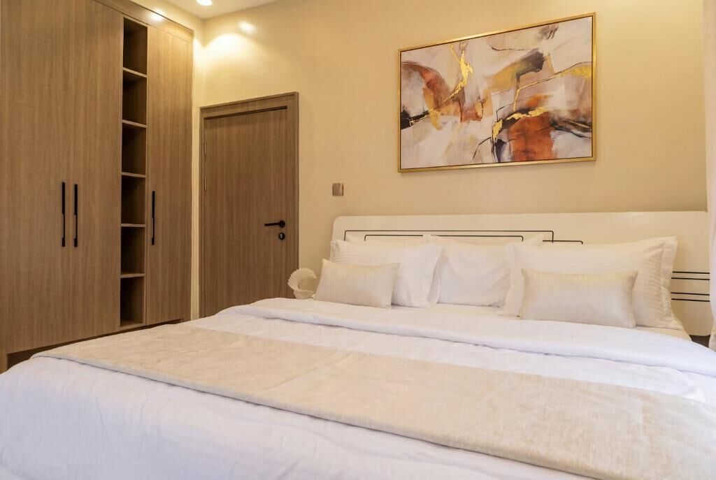 Un dormitorio con cama, armario y un cuadro en la pared.