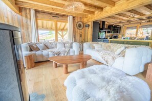A cozy wooden interior with a sofa, a coffee table, and a fluffy rug. - Jenepi - Chalet neuf 12 p - spa & playroom (Xonrupt-Longemer)