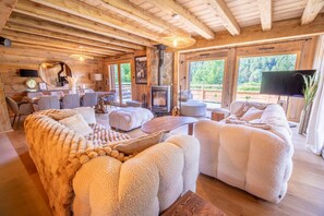 A cozy cabin interior with a fireplace, plush seating, and large windows. - Jenepi - Chalet neuf 12 p - spa & playroom (Xonrupt-Longemer)