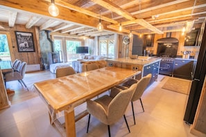 Un interior de madera con una mesa de comedor, sillas, una zona de cocina y un televisor.