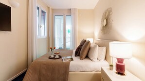 Une chambre d’hôtel avec un lit, une table de chevet, une lampe et une vue sur l’extérieur par une fenêtre.