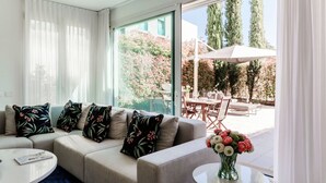 Un salon moderne avec un canapé, une table basse ronde et une vue sur un espace patio extérieur.
