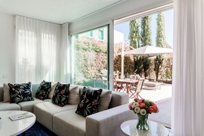 Ein modernes Wohnzimmer mit einer Couch, einem runden Couchtisch und Blick auf eine Außenpatio-Terrasse.