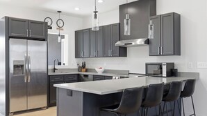 A modern kitchen with a large island, stainless steel appliances, and dark cabinetry.