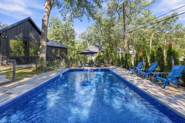 Une piscine avec des chaises longues et une structure en bois.