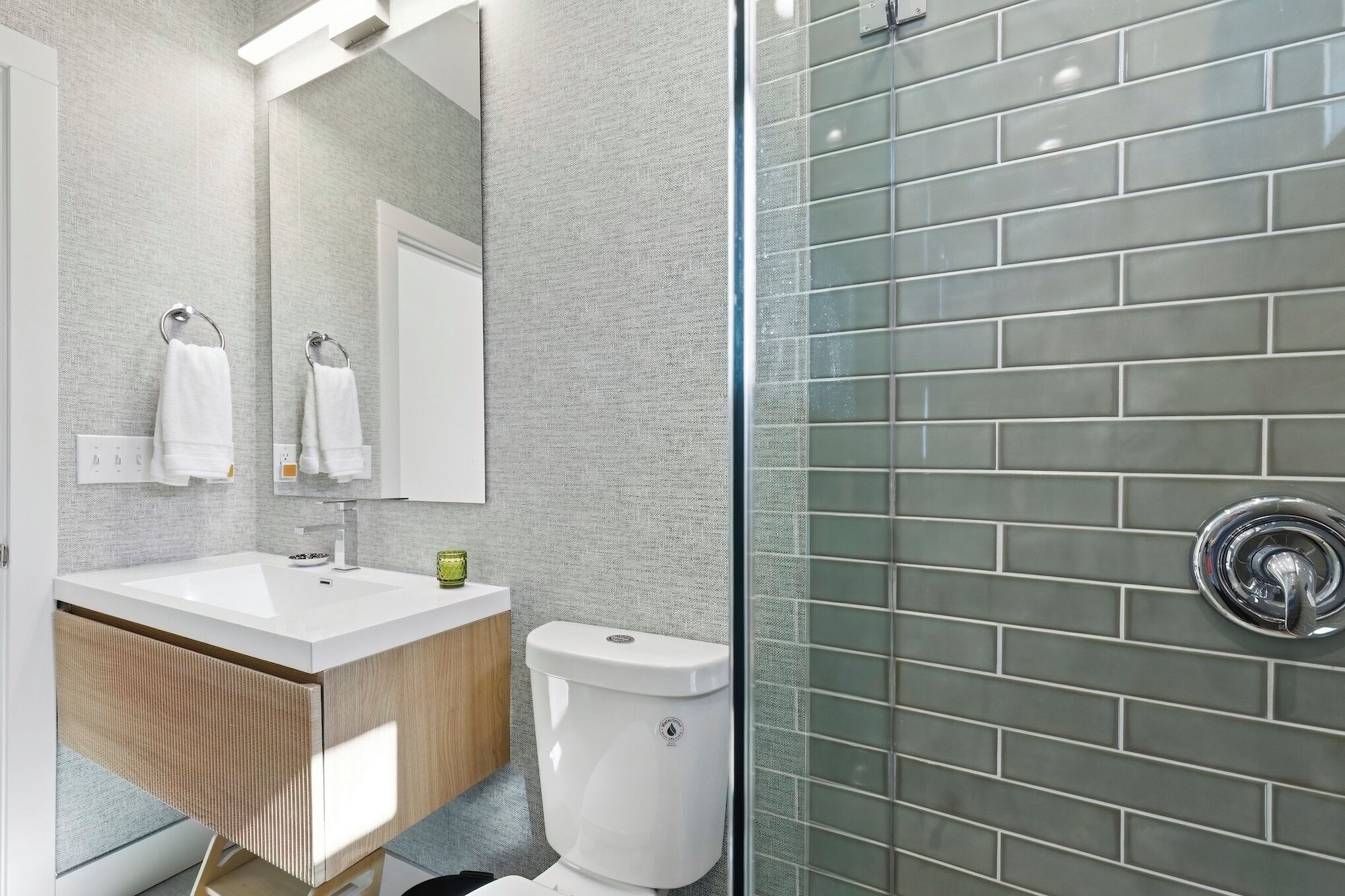 Une salle de bain moderne avec un lavabo blanc, un miroir et des toilettes.