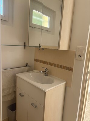 Ein Badezimmer mit Waschbecken, Spiegel, Schrank und Fenster.