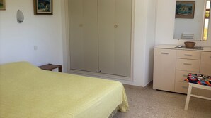 Ein Schlafzimmer mit einem Bett, einem Kleiderschrank, einem Schminktisch, einem kleinen Tisch und einer Wandleuchte.