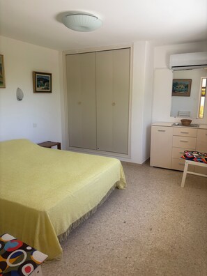 Ein Schlafzimmer mit Bett, Kleiderschrank, Schminktisch, Stuhl und einer Deckenleuchte.