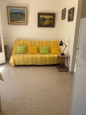 Ein Zimmer mit einer Couch, einer Lampe und drei gerahmten Bildern an der Wand.