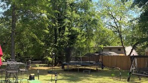 A backyard with a trampoline, a covered play area, and a dining table with chairs. - Charming 3-bedroom house in soothing Decatur comfortable and clean (Decatur)