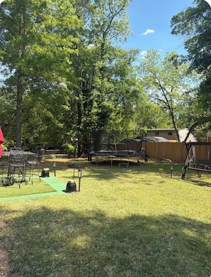 Ein Garten mit Trampolin, überdachtem Spielbereich und Essplatz mit Stühlen.