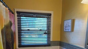 A bathroom with a toilet, sink, window with blinds, and a shower curtain. - Charming 3-bedroom house in soothing Decatur comfortable and clean (Decatur)
