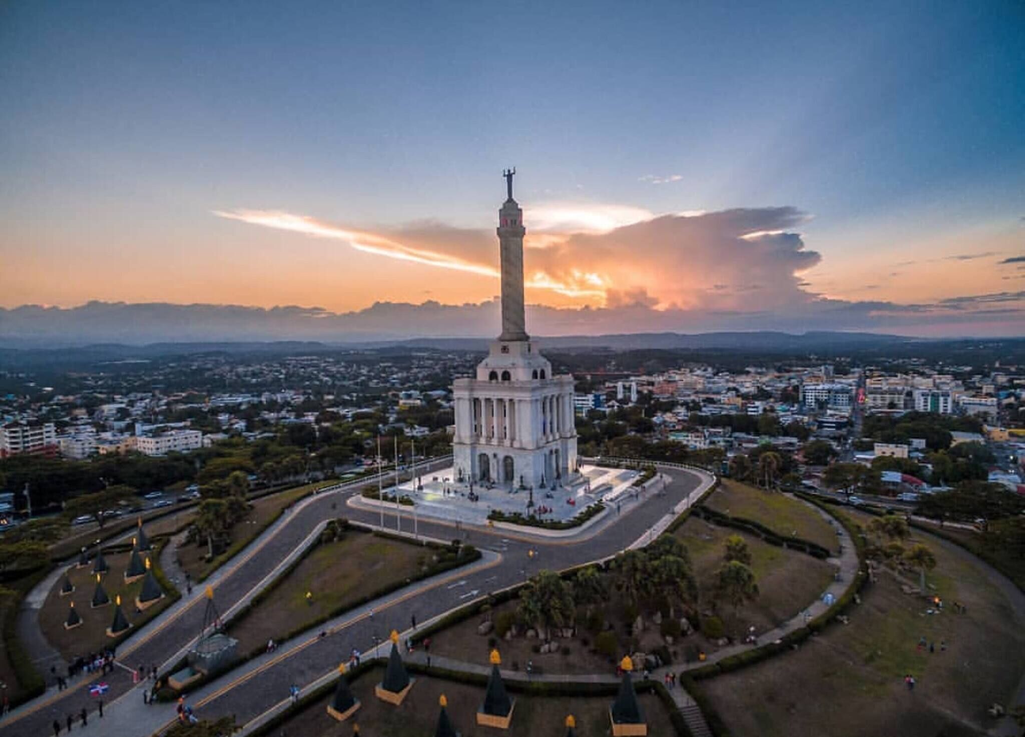 A large, white monument with a tall tower, surrounded by a landscaped area with pathways and trees.