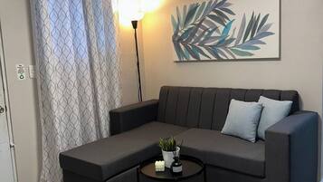 Una sala moderna con un sofá modular, una mesita redonda con una planta y una obra de arte colgada en la pared.