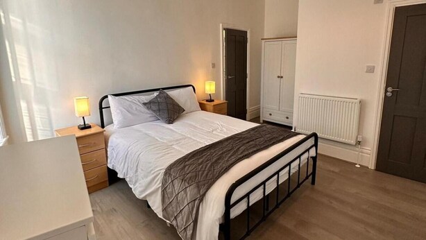 A bedroom with a bed, bedside tables, a radiator, and a wardrobe. - Near Beach - Parking - Wifi - Sleeps 2 (Lytham St. Anne's)