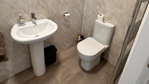 A bathroom with a white sink, toilet, and a trash bin. - Near Beach - Parking - Wifi - Sleeps 2 (Lytham St. Anne's)
