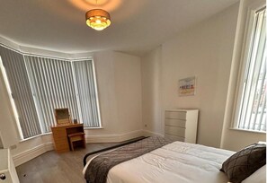 A bedroom with a bed, a dresser, a desk, a radiator, and a window with blinds. - Near Beach - Parking - Wifi - Sleeps 2 (Lytham St. Anne's)