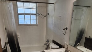 A bathroom with a bathtub, toilet, sink, and a window. - Nice 3-bedroom house with AC in peaceful Lubbock neighborhood (Lubbock)