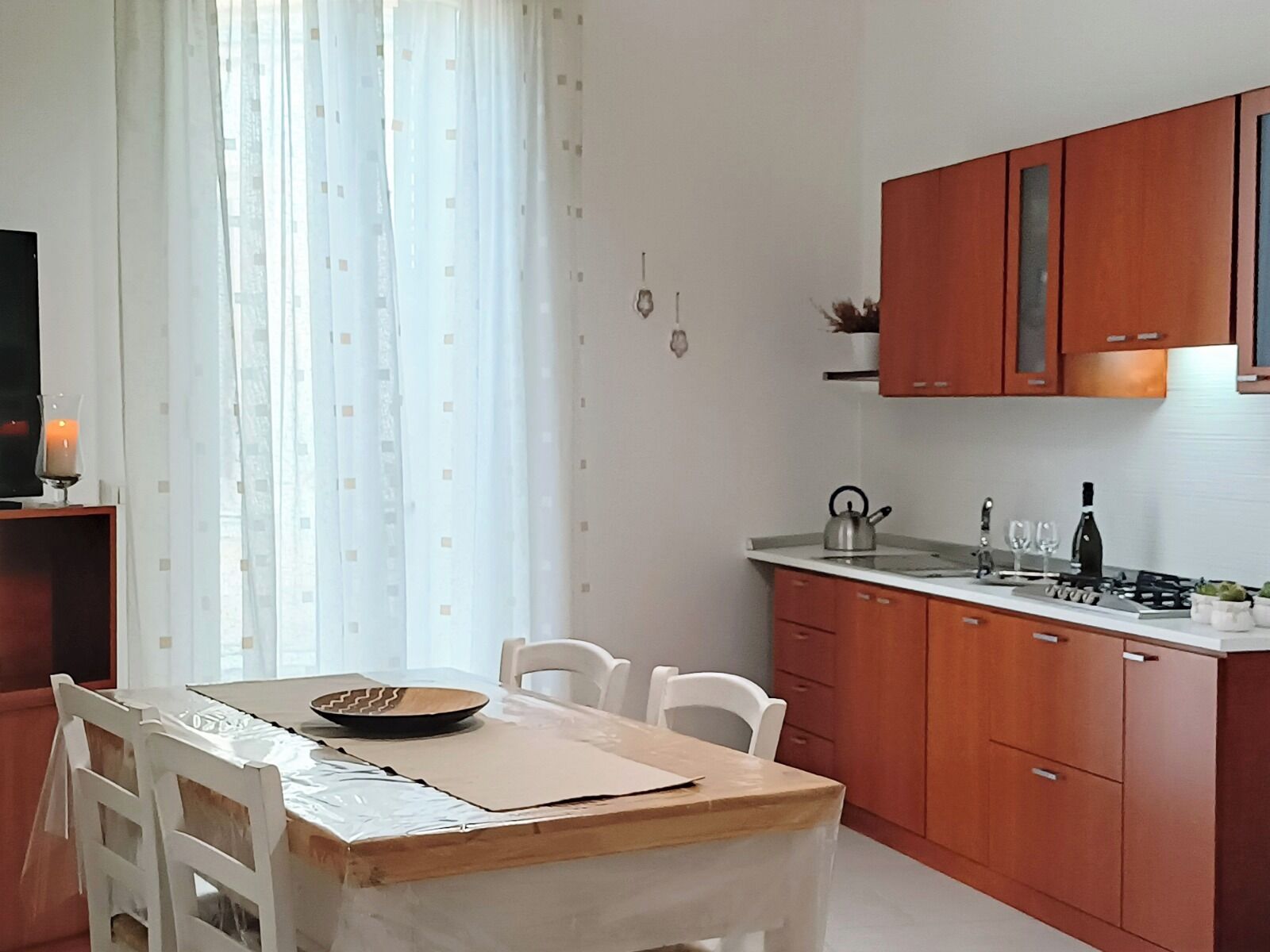 A modern kitchen with wooden cabinets, a gas stove, and a dining area with a table and chairs.