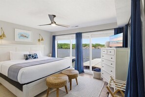 Ein Schlafzimmer mit Bett, Kommode, Fernseher und einem Balkon mit Blick.
