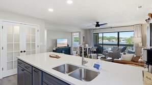 Una cucina moderna con una grande isola, un'area pranzo con posti a sedere all'aperto e vista mare.