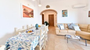 A dining area with a table set for four, a sofa, and a coffee table. - Relais Maison de Charles (Ischia)