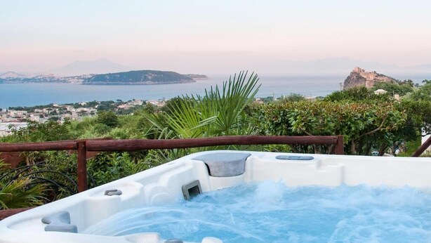 A hot tub with a view of the sea and a distant mountain. - Relais Maison de Charles (Ischia)